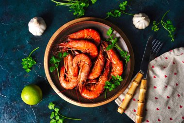 Pişmiş karides ve langoustine, limonlu kral karidesi, sarımsak ve maydanoz. Koyu mavi arka planda ızgara ve kızarmış.