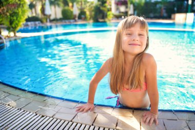 Tatlı çocuk ya da kız çocuk havuzda mayo giyer ve su parkında öğrenme, yüzme ya da dinlenme eğitimi için mutlu bir şekilde gülümser ve yaz tatilinde egzersiz yapar.