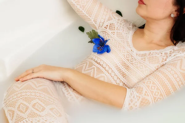 Vista superior de jovem, mulher sensual desfrutando de banho de leite com flores azuis — Fotografia de Stock