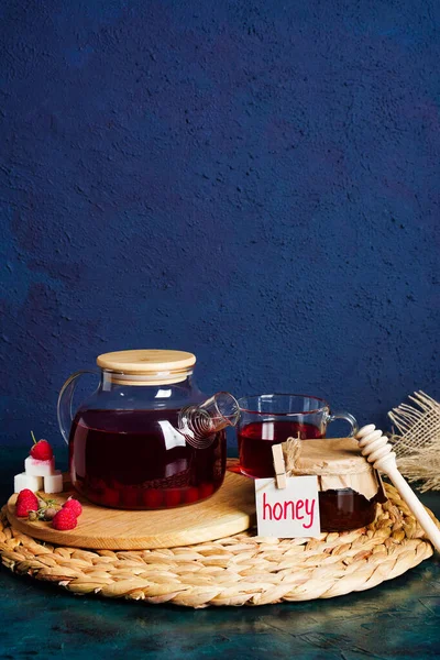 Honey, berry fruit tea and honeysuckle on dark blue background