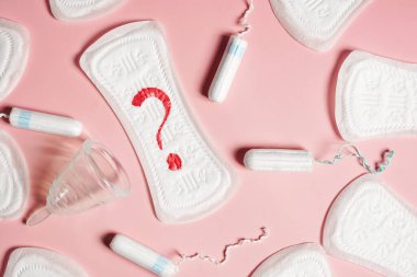 Kapalı ped, regl kupası, pembe arka planda tampon. Manzara düz. Kritik günler kavramı, adet görme