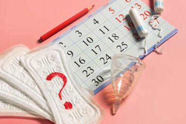 Kadın adet bardağı, tampon, takvim, normal döngünün kontrolü, kalem ve hijyenik ped peçetesi.