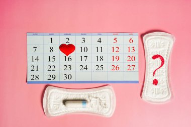 Adet günleri ürünleri, kırmızı kalp ve takvim pembe arka planda kırmızı işaretli adet günleri