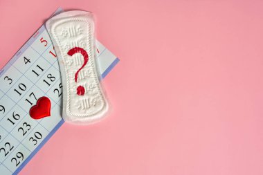 Adet günleri ürünleri, kırmızı kalp ve takvim üzerinde kırmızı işaretli regl tarihleri ve fotokopi alanı olan pembe arkaplan