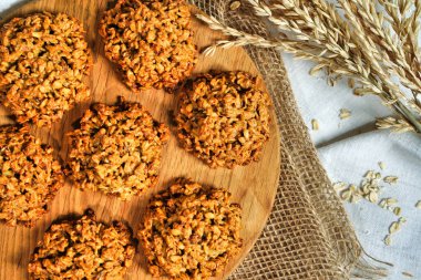 Yulaf ezmeli kurabiyeler yakın çekim odaklı mı yoksa sağlıklı mısır gevreği krakerleri mi? Kırsal masada yulaf ezmeli gevrek anzak bisküvisi.