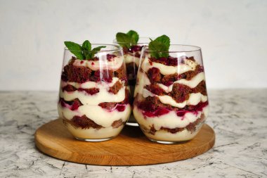 Şeffaf bardakta çikolatalı ve beyaz kremalı kahverengi süngerli tatlı. Pasta nane yaprağı ve doğum günü pastasıyla süslenmiş. Yüksek kalite fotoğraf