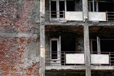 Terk edilmiş çok katlı bir binanın parçalarını kapatın. Mahvolmuş balkonlar, pencere ve kapı yok. Yüksek kalite fotoğraf