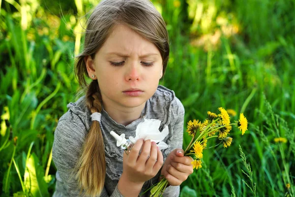 Child with pollen allergy. Girl sneezing and blowing nose because of seasonal allergy. Spring allergy concept. Flowering bushes and trees in background. Child allergy. High quality photo