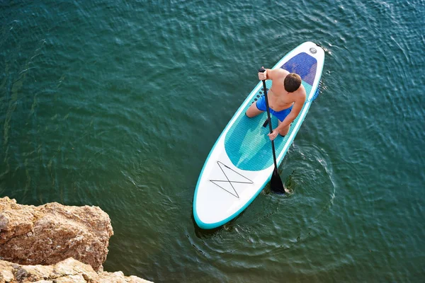 Top view on Paddleboard SUP Man having fun paddle board. Fitness recreational leisure activity. Beach rental equipment on travel vacation. High quality photo
