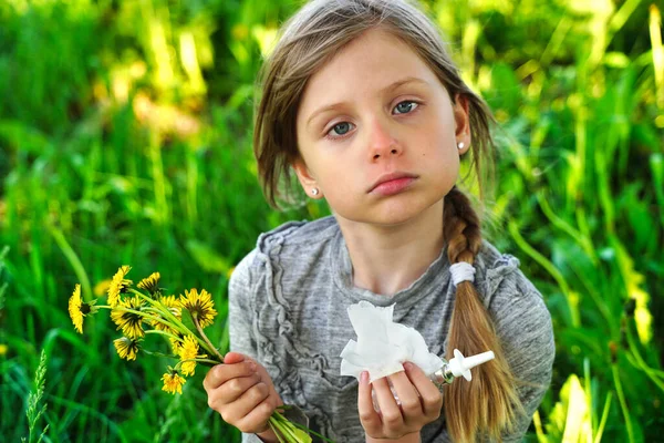 Child with pollen allergy. Girl sneezing and blowing nose because of seasonal allergy. Spring allergy concept. Flowering bushes and trees in background. Child allergy. High quality photo