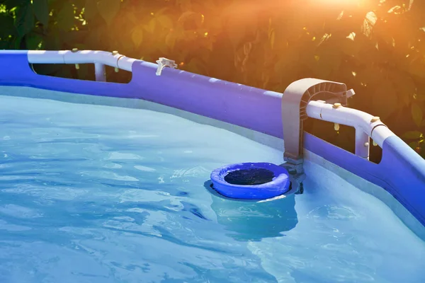 Skimmer on a round frame pool of a country house. Blue skimmer to clean pool in clear water. High quality photo