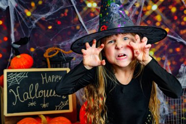 Cadılar Bayramı arka planında cadı kostümü giymiş kızgın küçük bir kızın portresi. Yüksek kalite fotoğraf