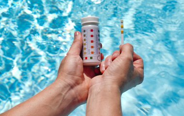 Bir havuzun su kalitesini PH değeri, klor ve yosun değeri olan bir test şeridi yardımıyla kontrol ediyorum. Yüksek kalite fotoğraf