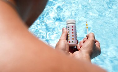 Bir havuzun su kalitesini PH değeri, klor ve yosun değeri olan bir test şeridi yardımıyla kontrol ediyorum. Yüksek kalite fotoğraf