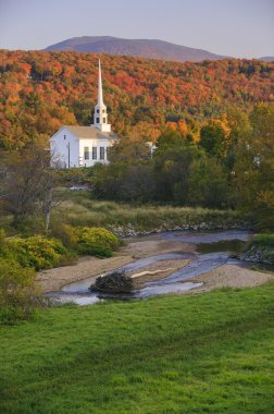 Fall foliage behind a rural Vermont church clipart