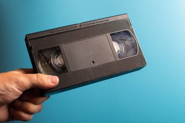 Elinde mavi arka planda retro HVS video kaseti var. Retro dalga. 80 'ler 90' lar