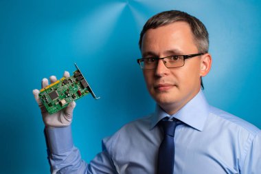 Mavi gömlekli, kravatlı ve gözlüklü bir adam bilgisayarın ağ kartını gösteriyor..