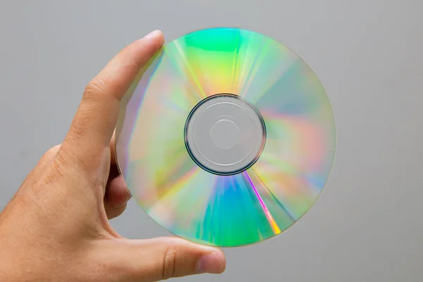 A hand holds a dvd disc in a close-up.