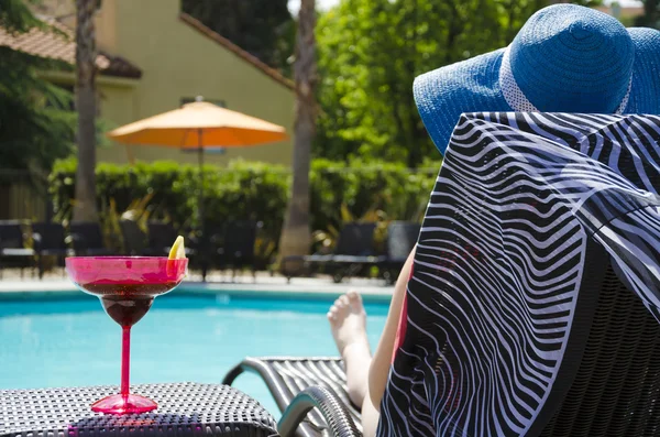 Дівчина з коктейльним напоєм біля басейну — стокове фото