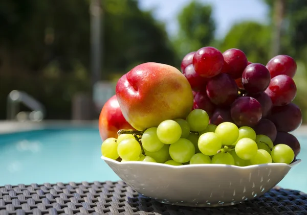 Pfirsiche und Trauben am Swimmingpool — Stockfoto