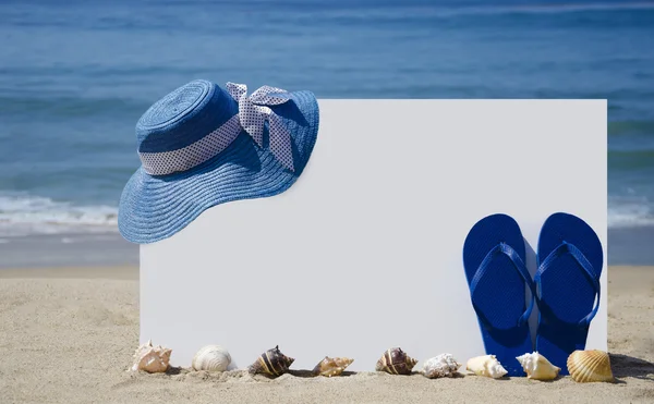 Tablero blanco con chanclas y sombrero en la playa de arena —  Fotos de Stock