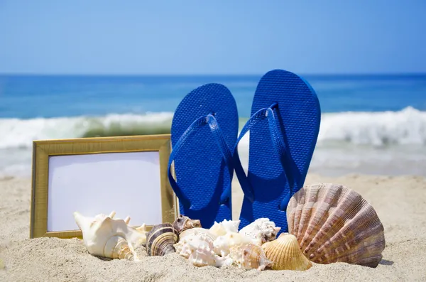 Chinelos com fotomoldura e conchas na praia de areia — Fotografia de Stock