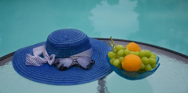 Sombrero y frutas junto a la piscina swimmimg — Foto de Stock