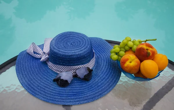 Sombrero y frutas junto a la piscina swimmimg — Foto de Stock