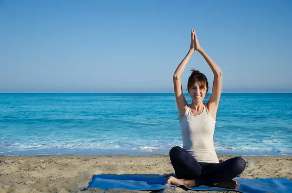 Yang kvinna utövar yoga av havet — Stockfoto