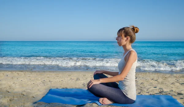 Yang kvinna utövar yoga av havet — Stockfoto