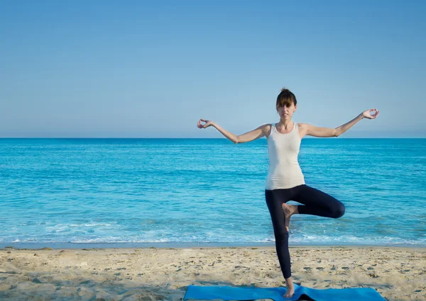 Yang kvinna utövar yoga av havet — Stockfoto