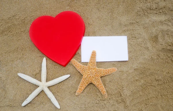 Heart shape, starfishes, and paper on the beach — Stock Photo, Image