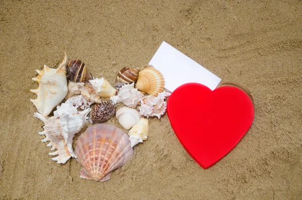 Zwei Herzformen und Papier am Strand — Stockfoto