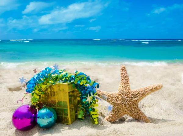 Seestern mit Weihnachtskugeln und Geschenk am Strand - Urlaub co — Stockfoto