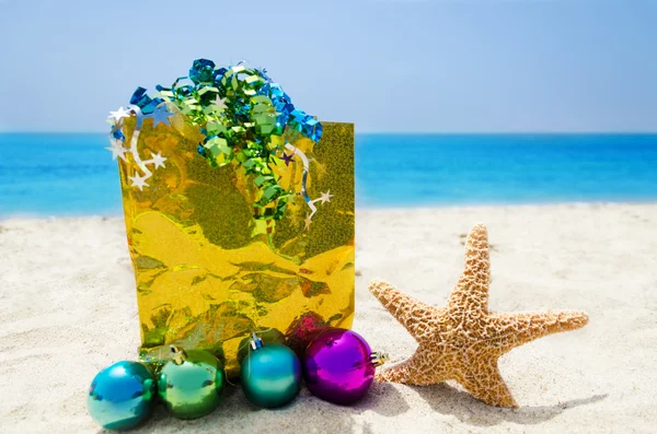 Seestern mit Weihnachtskugeln und Geschenk am Strand - Urlaub co — Stockfoto