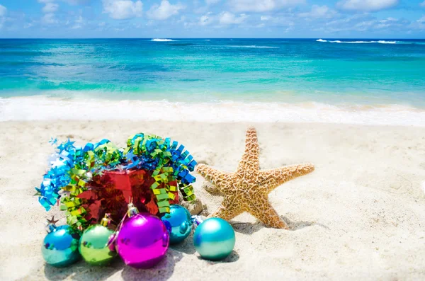 Starfish with Christmas balls and gift on the beach - holiday co — Stock Photo, Image