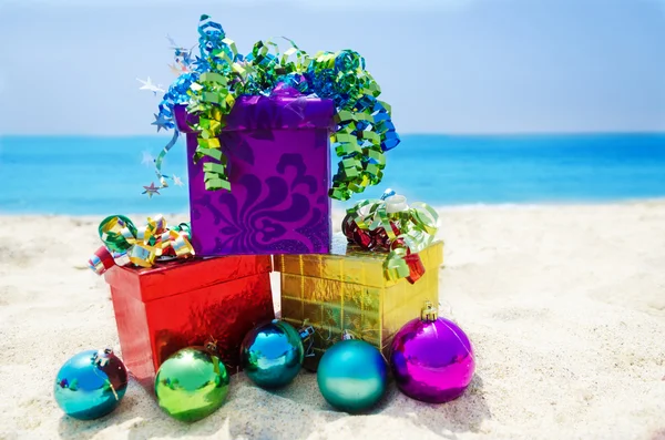 Scatole regalo con palline di Natale sulla spiaggia - concetto di vacanza — Foto Stock