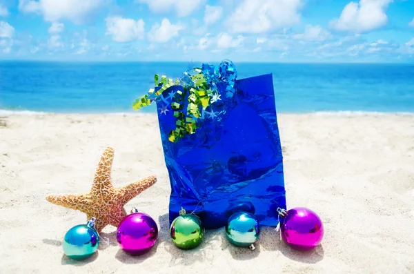 Stella marina con palline di Natale e sacchetto regalo sulla spiaggia — Foto Stock