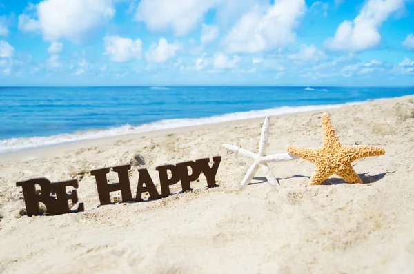 Знак "бути щасливим" і два starfishes з піщаний пляж — стокове фото