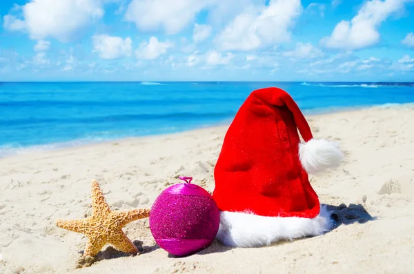 Chapéu de Natal com bola de Natal e estrela do mar na praia — Fotografia de Stock