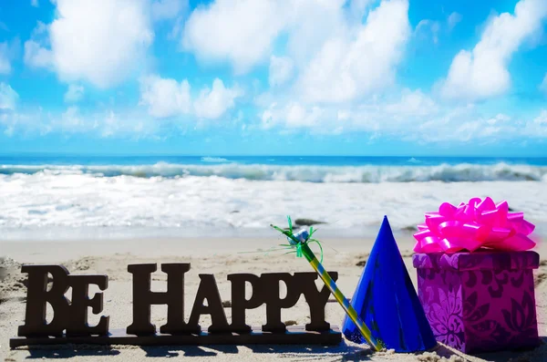 Firma "Sé feliz" con decoraciones de cumpleaños en la playa — Foto de Stock