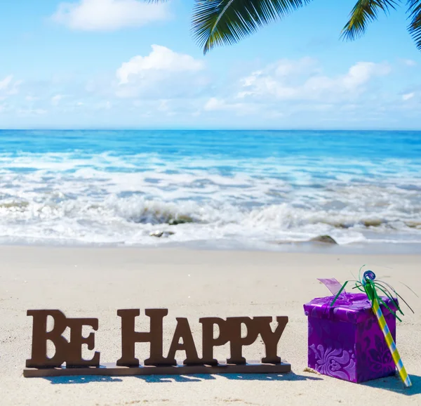 Schild "Sei glücklich" mit Geburtstagsdekoration am Strand — Stockfoto