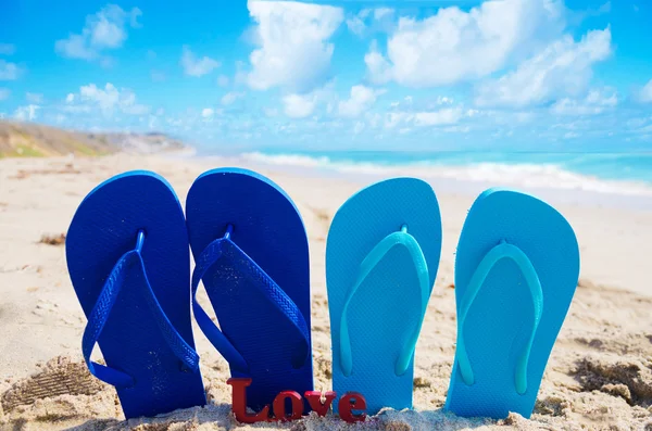 Slippers met teken "love" op het strand — Stockfoto