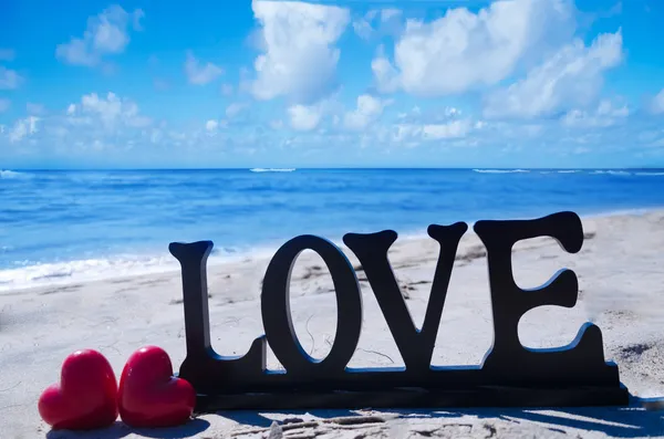 Sign "LOVE" with hearts on the beach — Stock Photo, Image