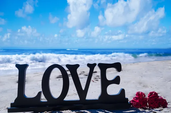 Sign "LOVE" with hearts on the beach — Stock Photo, Image