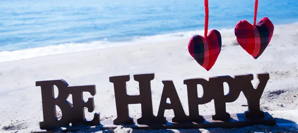 Registrera "vara lycklig" med hjärtat på stranden — Stockfoto