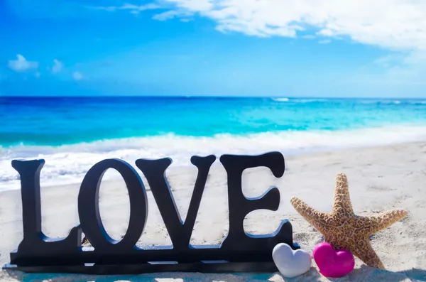 Sign "Love" with heart shapes and starfish — Stock Photo, Image