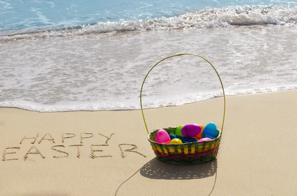 Assine "Feliz Páscoa" com cesta na praia — Fotografia de Stock