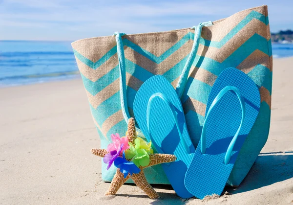Bolsa de playa con chanclas junto al océano —  Fotos de Stock