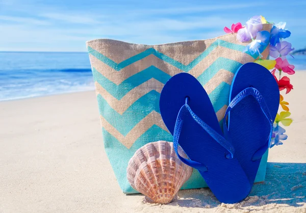 Bolsa de praia com chinelos junto ao oceano — Fotografia de Stock